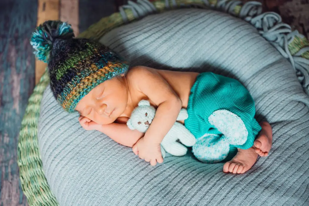 Child in knitted hat sleeps on large blue pillow
