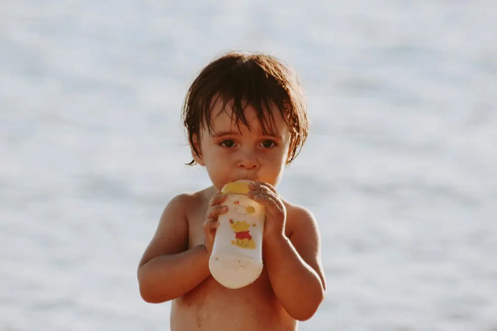 200 Place Inspired Boy Names That Are Unique and Exotic 6 A Toddler Drinking Milk from the Baby Bottle while on the Beach