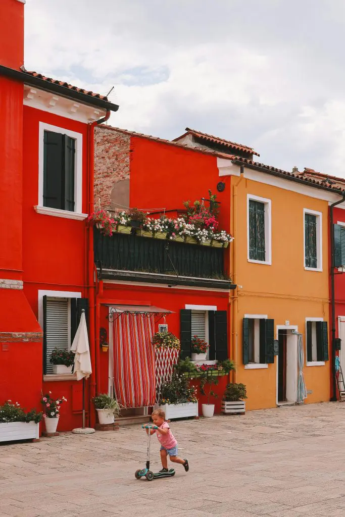 Child on Scooter in front of Colorful Townhouses