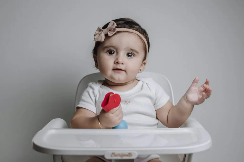 Unique Girl Names That Start With A 15 Baby Girl Sitting on a Feeding Chair with a Toy
