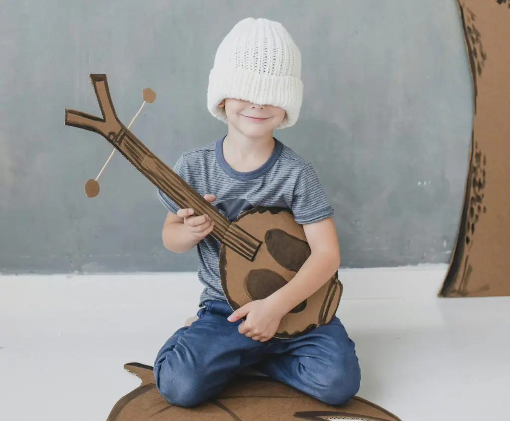 100 Romantic Boy Names That Will Steal Your Heart 18 Little boy in white hat with toy dombra