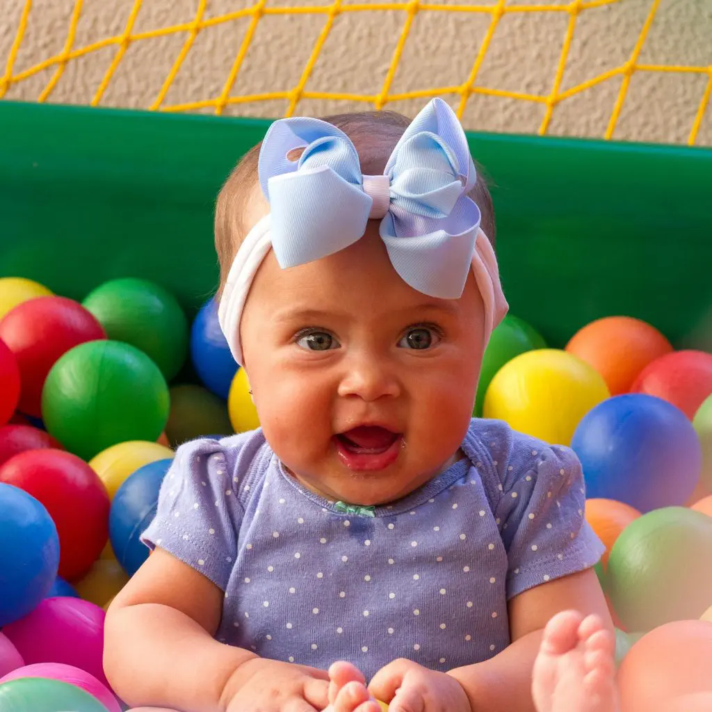 100+ Unique Girl Names That Start With G 9 Cute Baby in Blue and White Polka Dot Shirt Surrounded by Plastic Balls