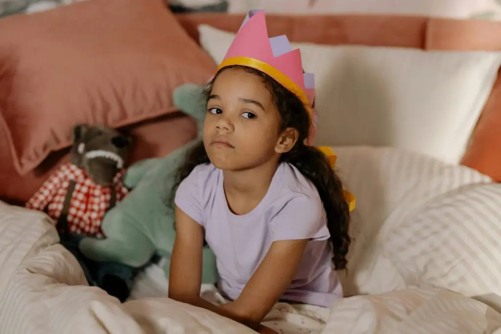 Kid Wearing Crown Sitting on Bed