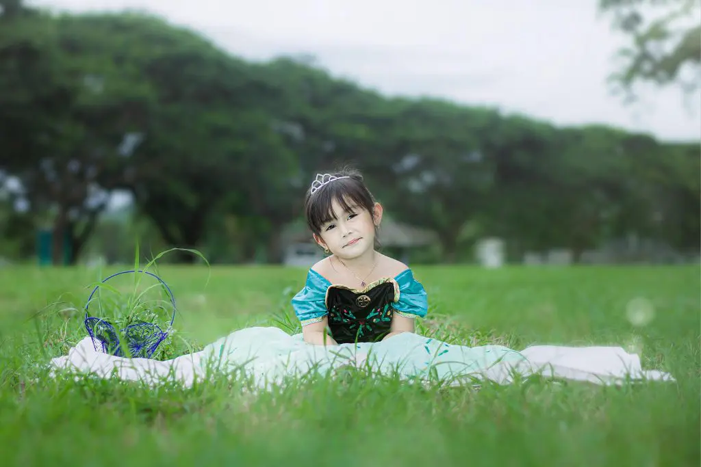 Girl Wearing a Princess Costume Sitting on Green Grass Field