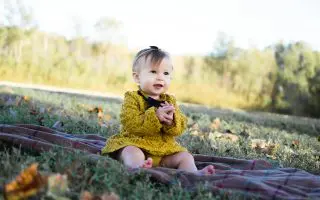 Baby Wearing Yellow Crochet Long Sleeve Dress Sitting on Brown Textile - Featured