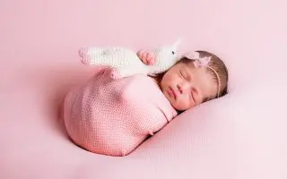 Adorable Newborn in Pink with Knit Unicorn Toy - Featured