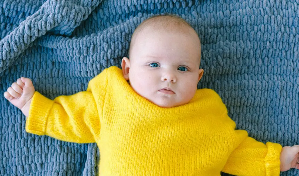 Cute toddler lying on knitted plaid before nap in bedroom - Featured