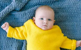 Cute toddler lying on knitted plaid before nap in bedroom - Featured