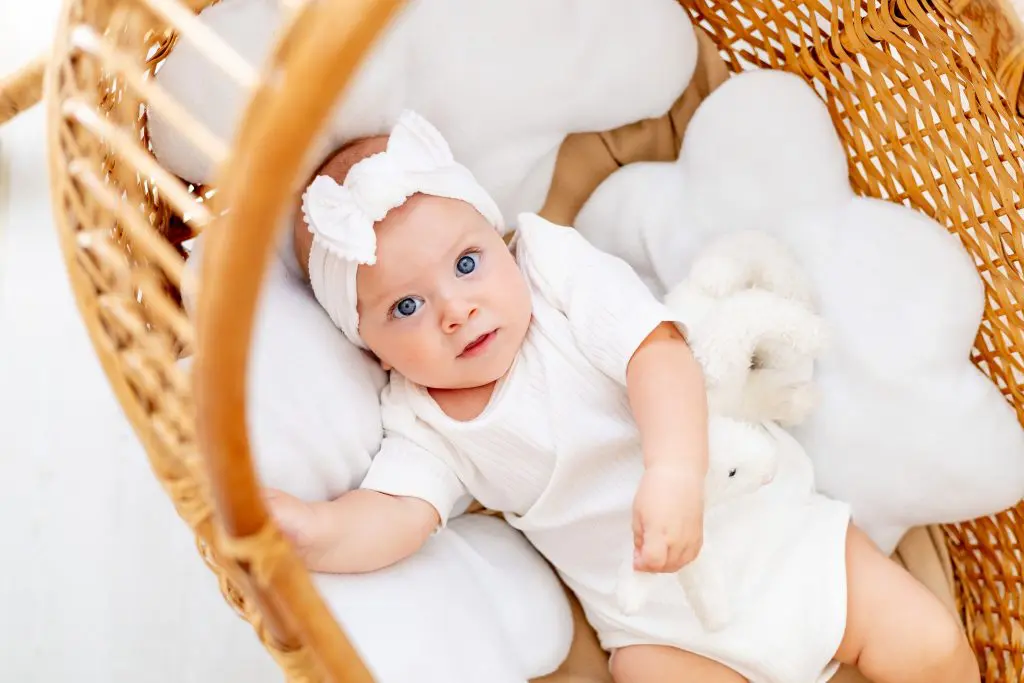 Happy joyful baby in a wicker crib