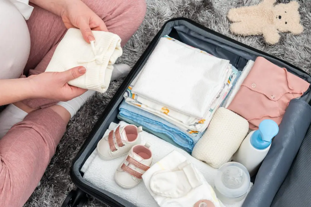 Woman packing baby clothing in suitcase