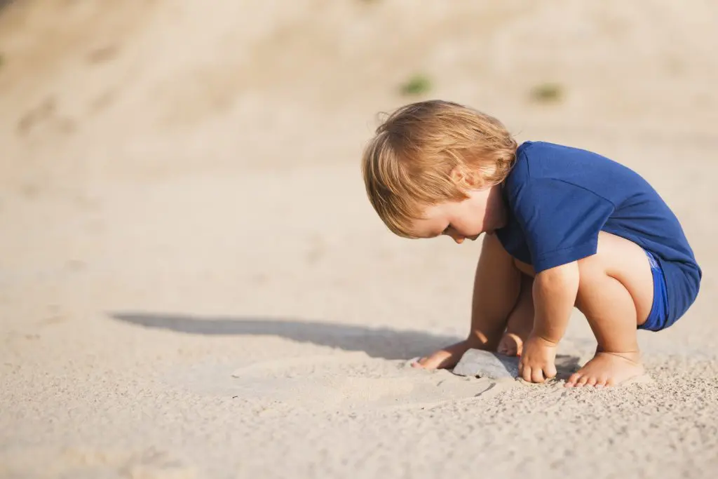 Little boy at beach playing with sand