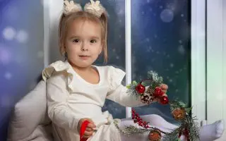 Little happy girl sitting on the windowsill
