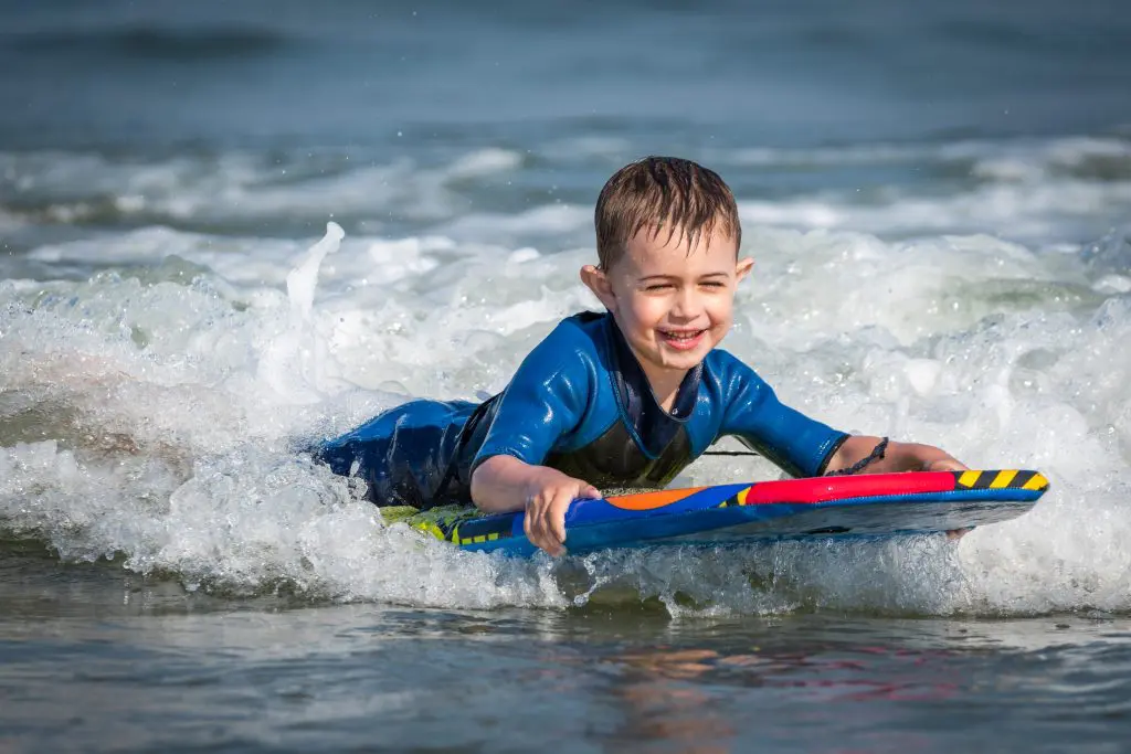 boy swimming in sea on kneeboard