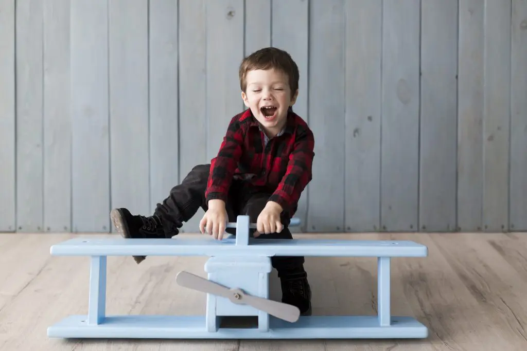 Kid playing on a wooden plane