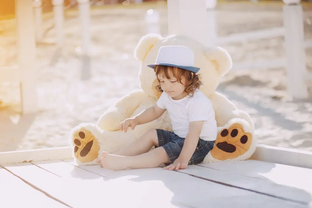 Little beautiful boy on the beach sitiing with his big toy