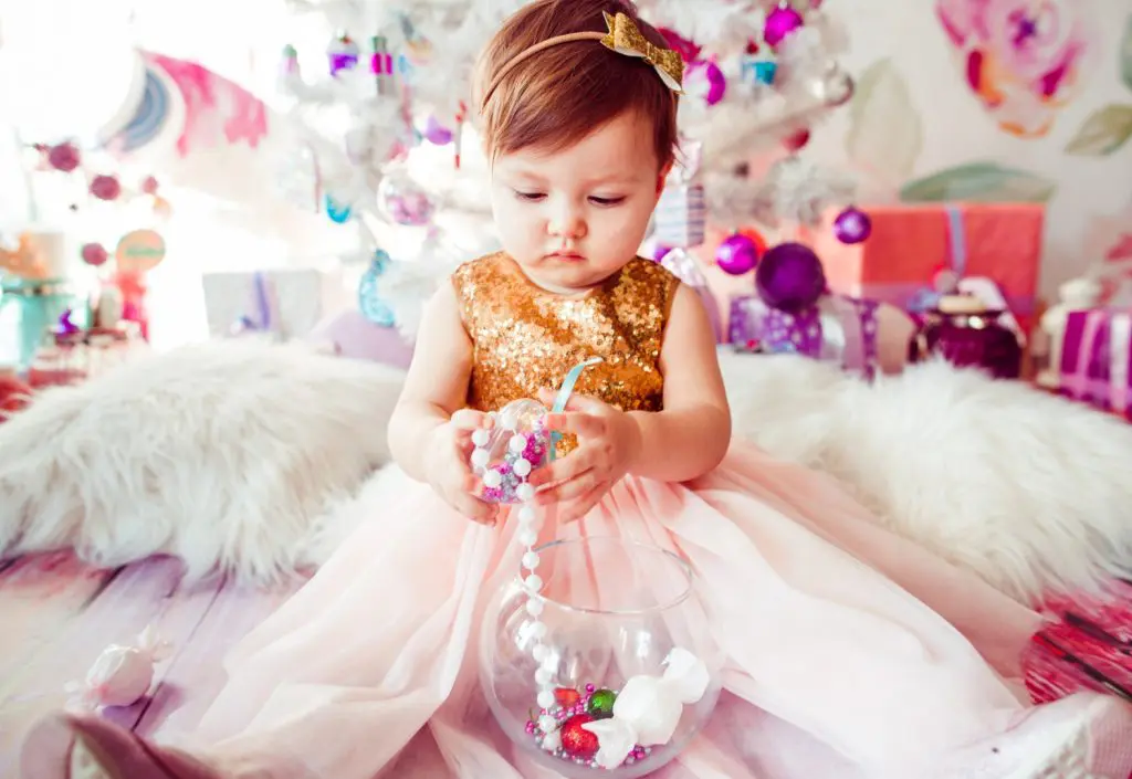 80 Gemstone Girl Names For Your Little Jewel 3 Little child in golden dress plays on the floor