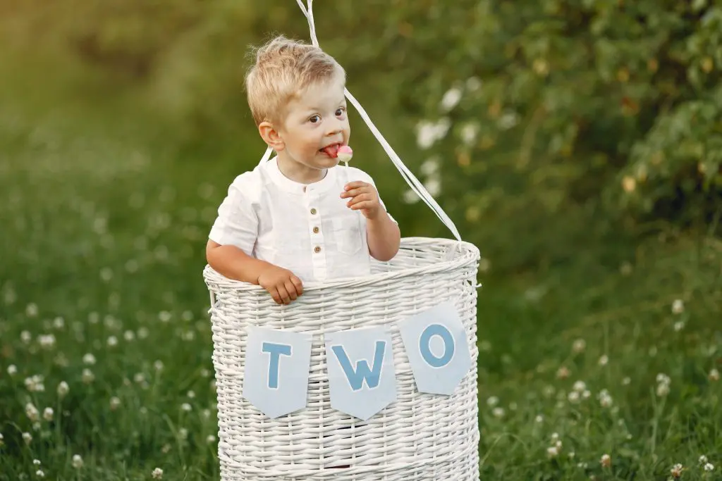 Little child sitting in the basket with balloons