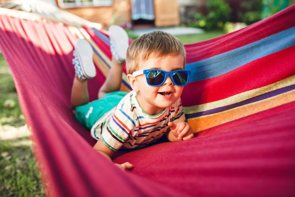 Little cute boy resting on bright hammock and having fun