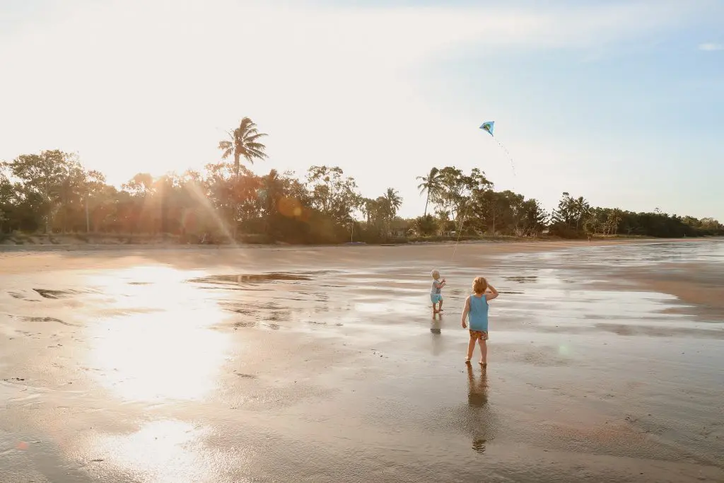Scenic view of two kids with blond hair playing with a kite