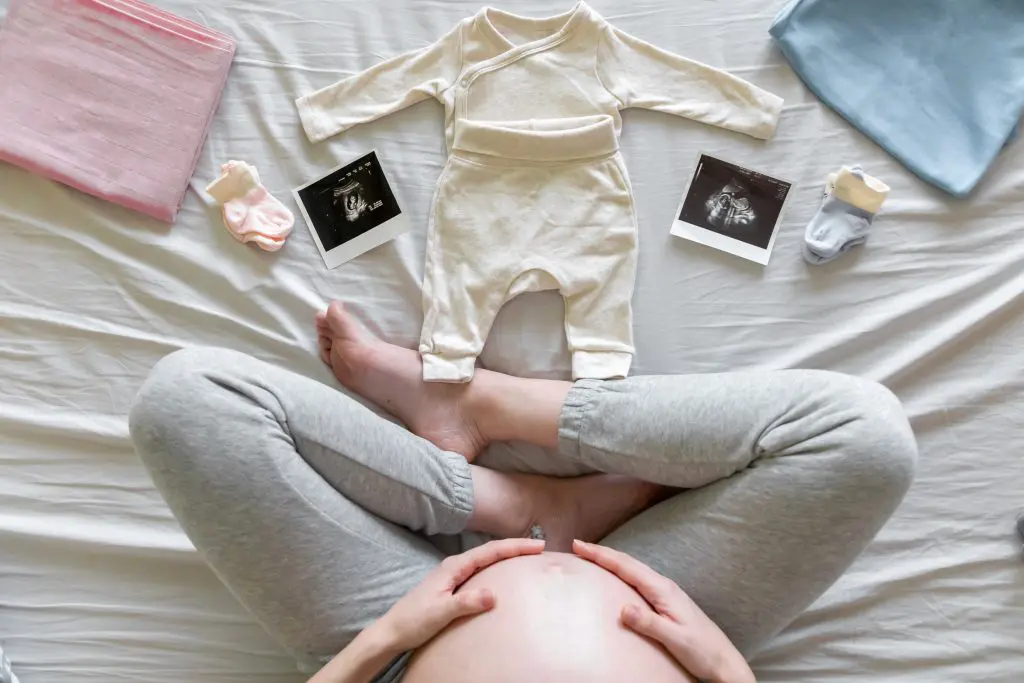 Top view of expecting pregnant woman in bed looking at ultrasound scans, boy or girl, pregnancy and birth concept