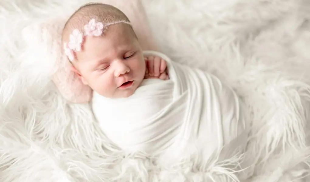 Newborn baby girl in swaddle blanket sleeping