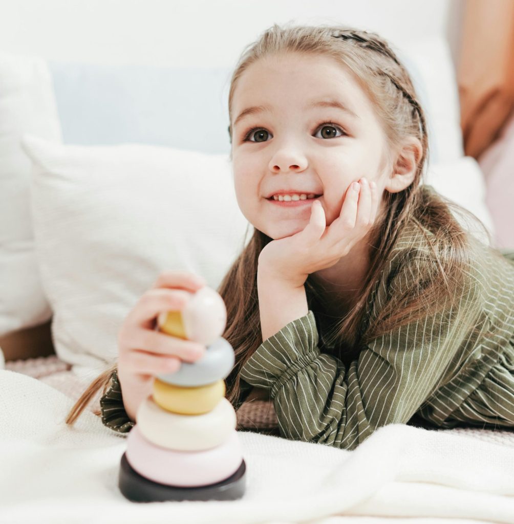 Photo of a Happy Kid Lying On White Bed