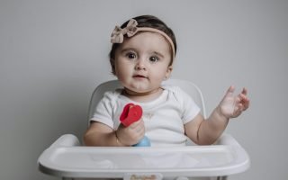 Baby Girl Sitting on a Feeding Chair with a Toy