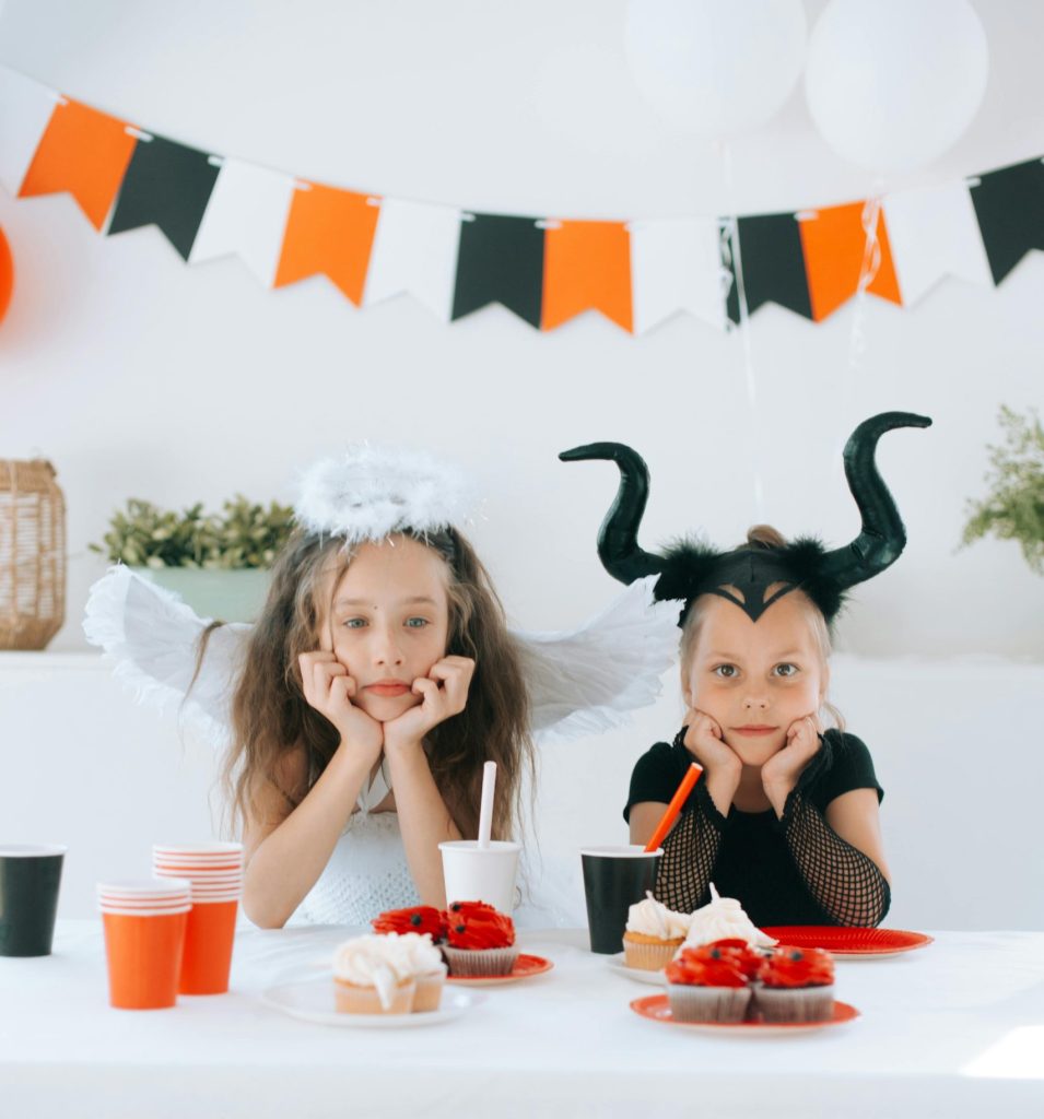 Two Girls in Halloween Costume Leaning on a Table