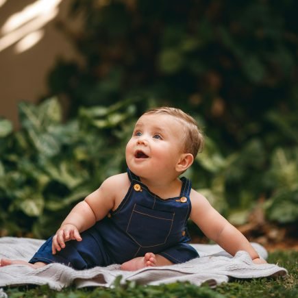 Baby in Jean Overalls Sitting on Blanket - Featured