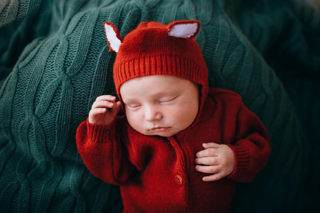 Funny cute newborn baby in knitted red woolen jumpers