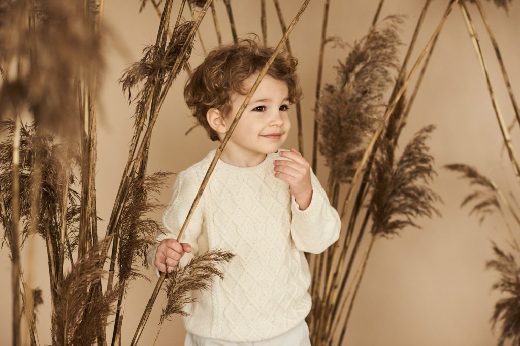 Beautiful smiling boy in a reed on a beige background