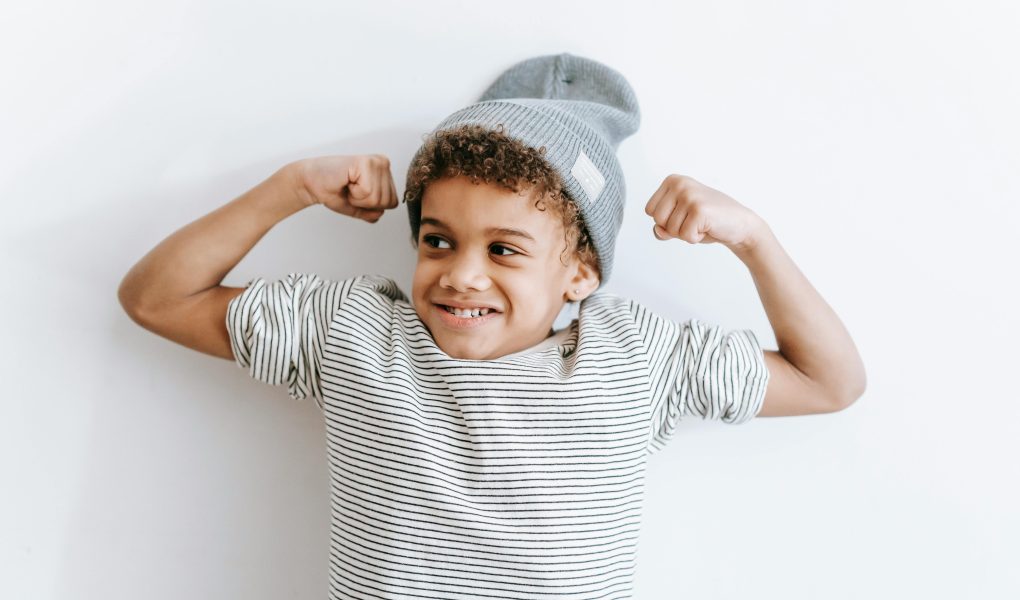 Cheerful black boy showing biceps - Featured