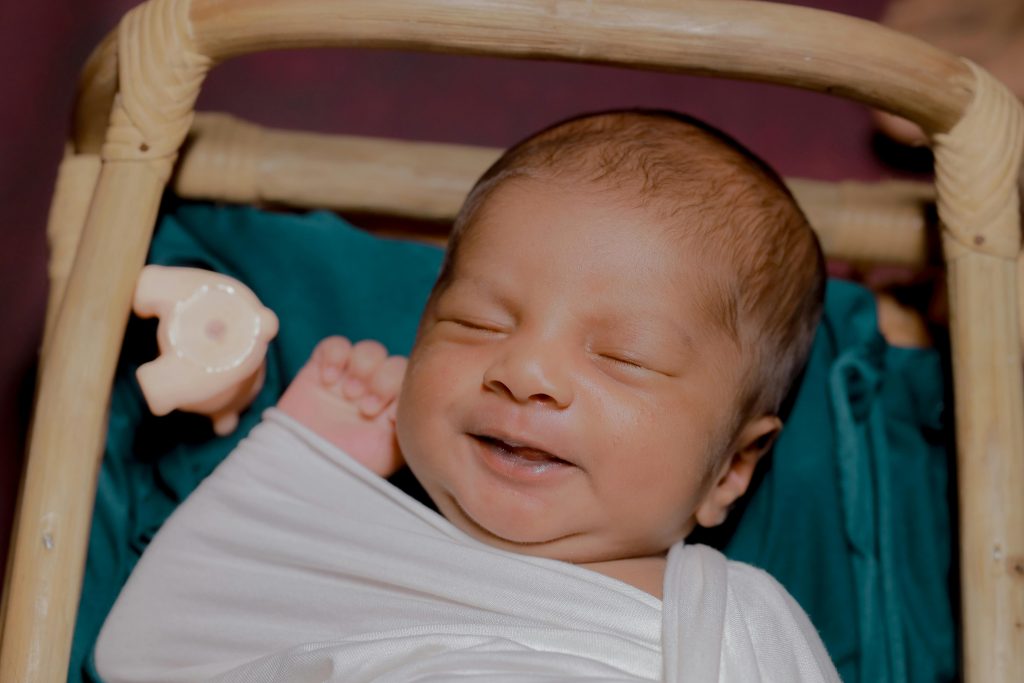 Smiling South Asian Baby in Cradle Indoors