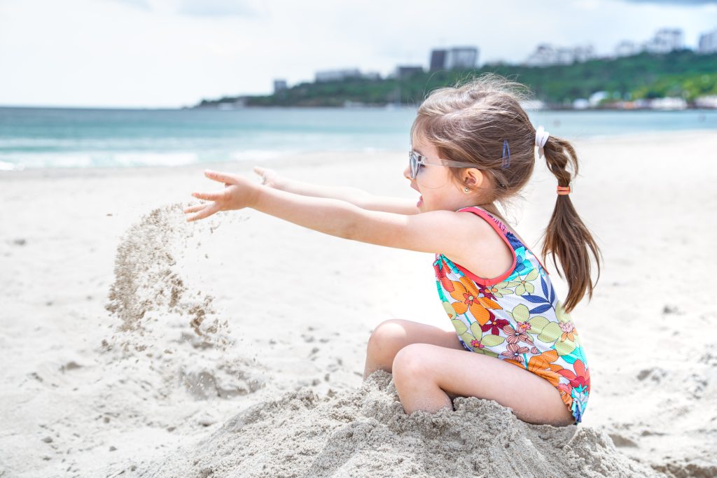 Small child tossing up the sand on the seashore