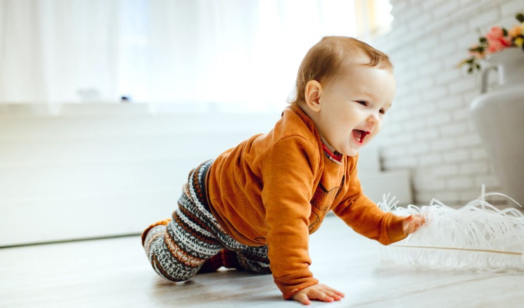 100 Modern Boy Names With Cool Nicknames 1 Happy child in orange sweater playing on the floor