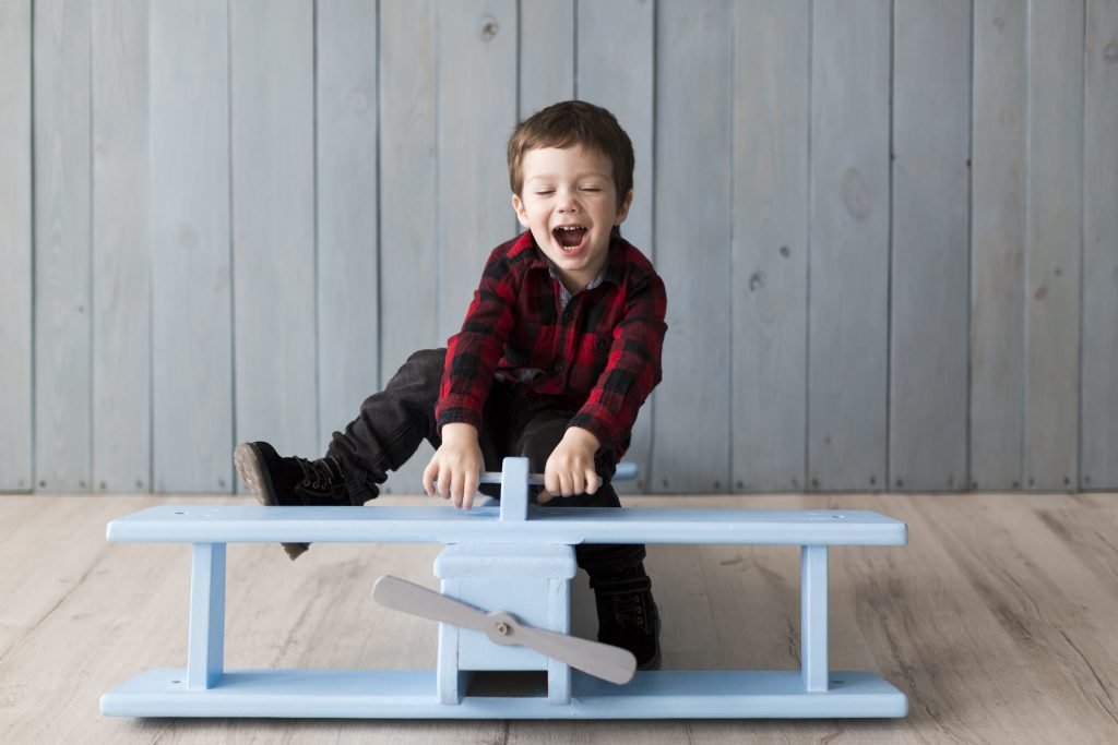 100 Modern Boy Names With Cool Nicknames 5 Kid playing on a wooden plane