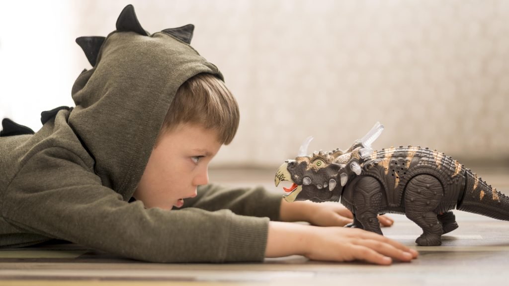 100 Modern Boy Names With Cool Nicknames 7 boy playing with dinosaur figure