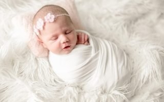 Newborn baby girl in swaddle blanket sleeping